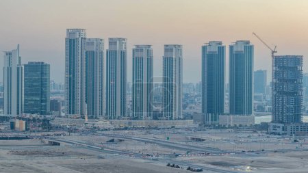 Foto de Rascacielos en Al Reem y Al Maryah Island en Abu Dhabi día a noche timelapse transición después de la puesta del sol desde arriba. Paisaje urbano aéreo de Al Reem Island con edificios iluminados - Imagen libre de derechos