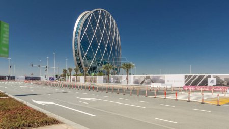 Foto de Rascacielos circular Aldar Sede Edificio timelapse hyperlapse en Abu Dhabi, Emiratos Árabes Unidos. Tráfico en la carretera. Es el primer edificio circular de este tipo en Oriente Medio. - Imagen libre de derechos