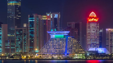 Téléchargez les photos : Doha gratte-ciel dans l'horizon du centre-ville timelapse nocturne, Qatar, Moyen-Orient Tours éclairées sur une baie ouest reflétées dans une eau du Golfe. - en image libre de droit