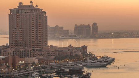 Foto de Tarde en el timelapse de día a noche de Pearl-Qatar desde arriba. Es una isla artificial en Qatar. Vista de la Marina y edificios residenciales en Porto Arabia en Doha, Qatar, Oriente Medio - Imagen libre de derechos