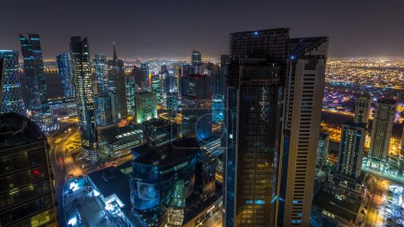 Photo for The skyline of the West Bay area from top in Doha timelapse, Qatar. Illuminated modern skyscrapers aerial view from rooftop at night - Royalty Free Image