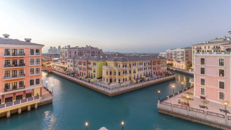 Téléchargez les photos : Vue aérienne sur le canal dans le quartier Qanat du quartier Pearl de Doha, comme à Venise, du jour à la nuit, période de transition temporelle, Qatar. Éclairage du soir réfléchi dans l'eau - en image libre de droit
