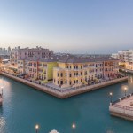 Canal aerial top view in Venice-like Qanat Quartier of the Pearl precinct of Doha day to night transition timelapse, Qatar. Evening illumination reflected in water