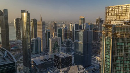 Téléchargez les photos : Skyline of West Bay and Doha City Center during sunrise timelapse, Qatar. gratte-ciel modernes tôt le matin avec des ombres se déplaçant sur elle - en image libre de droit