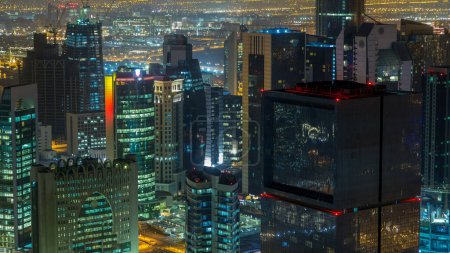 Foto de El horizonte de la zona de West Bay desde arriba en Doha timelapse, Qatar. Rascacielos modernos iluminados vista aérea desde la azotea por la noche - Imagen libre de derechos