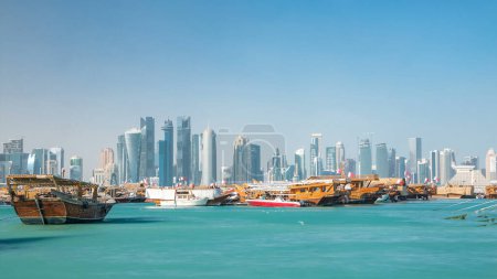 Foto de Una vista panorámica del antiguo puerto de dhow timelapse en Doha, Qatar, con el horizonte de West Bay en el fondo. Rascacielos modernos en el fondo y barcos antiguos en primer plano. - Imagen libre de derechos