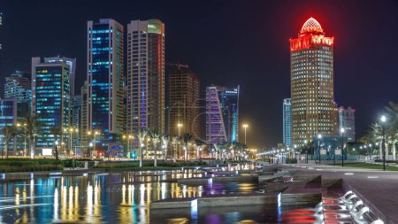 Téléchargez les photos : L'horizon de Doha de nuit avec un ciel étoilé vu depuis Park timelapse, Qatar. gratte-ciel et tours éclairés réfléchis dans l'eau de fontaine - en image libre de droit