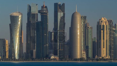 Téléchargez les photos : Skyline de la ville arabe de Doha timelapse au Qatar, capturé très tôt le matin au lever du soleil avec les riches couleurs chaudes du soleil reflétant les gratte-ciel en verre. - en image libre de droit