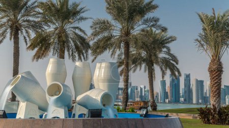Photo for Corniche in Doha with the water pots fountain landmark timelapse, with the distant business towers skyline. Islamic museum is in the background. - Royalty Free Image