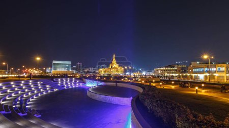Téléchargez les photos : Petit amphithéâtre dans le parc Souq Waqif la nuit hyperlapsus timelapse à Doha, avec végétation et bâtiments au loin, y compris le centre islamique illuminé. - en image libre de droit