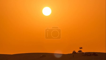 Photo for Buggies in sand desert and paraglider at the sunset timelapse. People and jeep cars on weekend. Close up view. Qatar - Royalty Free Image