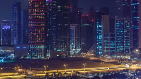 Photo for The skyline of the West Bay area from top in Doha timelapse, Qatar. Illuminated modern skyscrapers aerial view from rooftop at night. Traffic on the road - Royalty Free Image