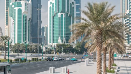 Foto de El distrito de gran altura de Doha timelapse con el tráfico en la intersección, visto desde el Parque del Hotel, con rascacielos y palmeras - Imagen libre de derechos