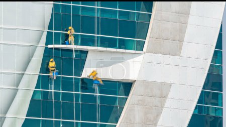 Foto de Trabajadores lavando ventanas del moderno edificio de rascacielos timelapse. Día soleado. Doha, Qatar - Imagen libre de derechos