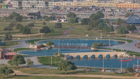 Téléchargez les photos : Pont avec fontaine et lac dans le parc Aspire timelapse à Doha, Qatar. Vue aérienne du dessus tôt le matin au lever du soleil - en image libre de droit