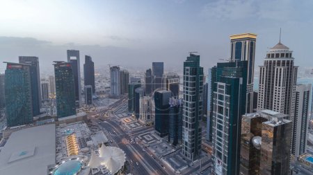 Téléchargez les photos : Skyline de la région de West Bay, du sommet à Doha, période de transition de jour à nuit, Qatar. gratte-ciel modernes éclairés vue aérienne depuis le toit le soir après le coucher du soleil. Trafic sur la route - en image libre de droit