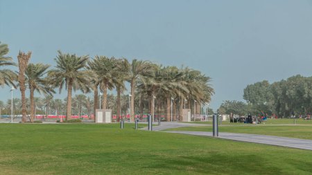 Photo for Palms in the MIA Park timelapse, located on one end of the seven kilometers long Corniche in the Qatari capital, Doha. Green grass and path. - Royalty Free Image