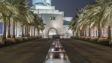 Photo for Museum of Islamic Art illuminated at night with fountain timelapse in Doha, Qatar. Palms on the side. It is one of the worlds most complete collections of Islamic artifacts - Royalty Free Image
