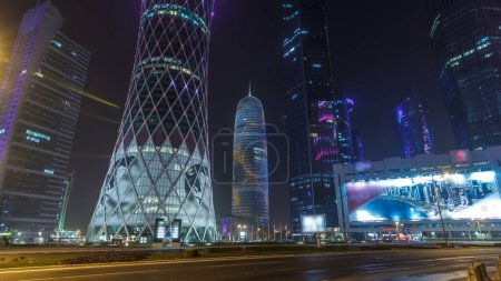 Téléchargez les photos : L'horizon de la région de West Bay à Doha est l'hyperlapsus intemporel, Qatar. Éclairage nocturne de gratte-ciel modernes. Trafic sur la route - en image libre de droit