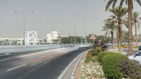 Foto de Monumento al Islamin. El timelapse simbólico de entrada del Parque Familiar Alrumeilah, detrás de la Corniche en Doha, Qatar. Tráfico en la carretera - Imagen libre de derechos