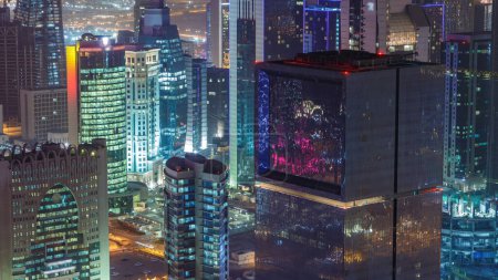 Foto de El horizonte de la zona de West Bay desde arriba en Doha timelapse, Qatar. Iluminado rascacielos modernos vista aérea desde la azotea por la noche. Tráfico en la carretera - Imagen libre de derechos