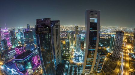 Photo for The skyline of the West Bay area from top in Doha timelapse, Qatar. Illuminated modern skyscrapers aerial view from rooftop at night. Traffic on the road. Fisheye lens - Royalty Free Image