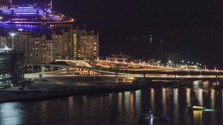 Foto de Vista aérea desde Dubai Marina timelapse noche para el tráfico en un puente de la isla de la palma jumeirah. Vista superior desde arriba con hoteles y villas iluminadas - Imagen libre de derechos