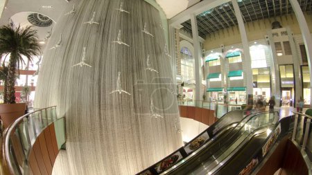 Téléchargez les photos : Cascade à l'intérieur du centre commercial avec foule sur l'escalator, plus grand centre commercial du monde, Dubaï, Émirats arabes unis timelapse - en image libre de droit