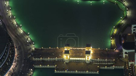 Téléchargez les photos : Pont illuminé avec promeneurs près de la plus grande fontaine musicale du centre-ville de Dubaï, Émirats arabes unis timelapse. Vue aérienne du point de vue - en image libre de droit