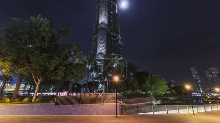 Photo for Dubai downtown and illuminated Burj Khalifa timelapse hyperlapse in Dubai, UAE. Tallest building in the world with moon behind, United Arab Emirates. - Royalty Free Image