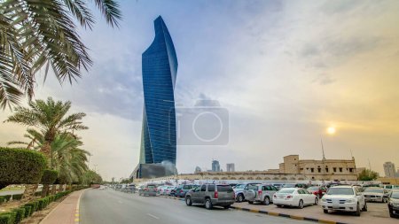Photo for Modern twisted Tower in Kuwait City timelapse hyperlapse. Kuwait, Middle East. With palms and traffic on the road at sunset time - Royalty Free Image