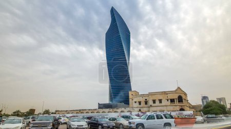 Foto de Moderna torre retorcida en Kuwait City timelapse hyperlapse. Kuwait, Oriente Medio. Con palmeras y tráfico en la carretera al atardecer - Imagen libre de derechos