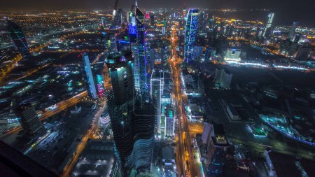 Photo for Skyline with Skyscrapers night timelapse in Kuwait City downtown illuminated at dusk. Aerial view from rooftop at foggy weather. Kuwait City, Middle East. - Royalty Free Image
