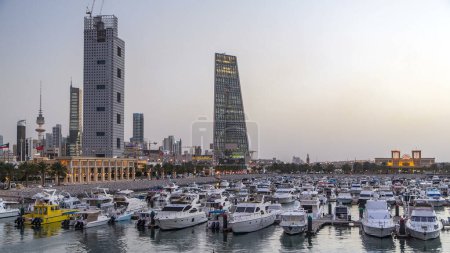 Téléchargez les photos : Yachts et bateaux à la marina Sharq avec des tours modernes jour à nuit transition timelapse hyperlapse au Koweït. Koweït, Moyen-Orient. Vue depuis le pont - en image libre de droit