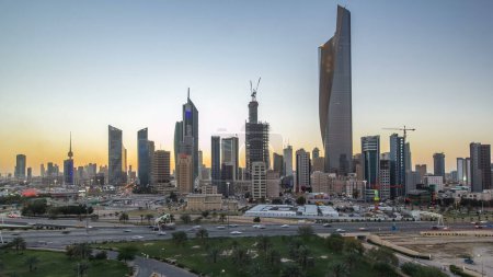 Foto de Skyline con rascacielos día a noche timelapse transición en el centro de Kuwait iluminado al atardecer. Vista aérea desde la azotea. Ciudad de Kuwait, Oriente Medio. - Imagen libre de derechos