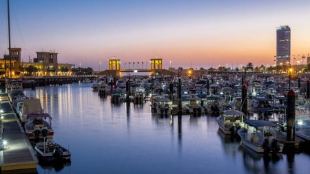 Foto de Yates y barcos en el puerto deportivo de Sharq con horizonte de la ciudad noche a día timelapse transición en Kuwait. Reflejo en el agua. Ciudad de Kuwait, Oriente Medio. - Imagen libre de derechos