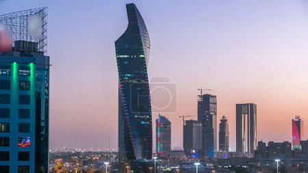 Foto de Skyline con rascacielos día a noche timelapse transición en la ciudad de Kuwait torres del centro iluminadas al atardecer. Vista aérea desde la azotea. Ciudad de Kuwait, Oriente Medio. - Imagen libre de derechos