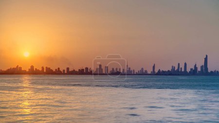 Téléchargez les photos : Vue panoramique du paysage urbain du Koweït pendant le coucher du soleil timelapse avec des gratte-ciel modernes reflétés dans l'eau - en image libre de droit