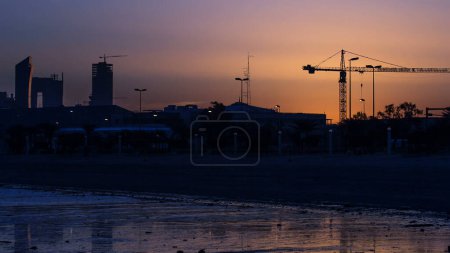 Foto de Horizonte costero de Kuwait ciudad sunrise timelapse. Torres modernas y rascacielos reflejados en el agua. - Imagen libre de derechos