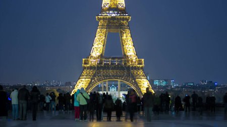 Photo for Eiffel Tower seen from Trocadero with crowd night timelapse with nice bokeh blur in Paris, France. Crowd of people walking on the square with a viewpoint. - Royalty Free Image