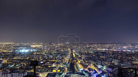 Téléchargez les photos : The city skyline at night from above. Paris, France. Aerial view from the tour Montparnasse panoramic timelapse with traffic on streets and railway station with trains - en image libre de droit