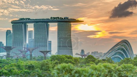 Photo for Marina Bay Sands, Gardens by the bay with cloud forest, flower dome and supertrees at sunset timelapse. Top view from marina barrage - Royalty Free Image