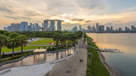 Téléchargez les photos : Panorama panoramique de Singapour près de Gardens by the bay avec forêt nuageuse, dôme de fleurs de jour à la nuit transition timelapse après le coucher du soleil. Vue de dessus depuis le barrage de la marina - en image libre de droit