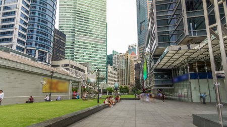 Foto de Rascacielos y torres en Raffles Place en Singapur Centro Financiero lapso de tiempo hiperlapso. Césped verde. Gente caminando - Imagen libre de derechos