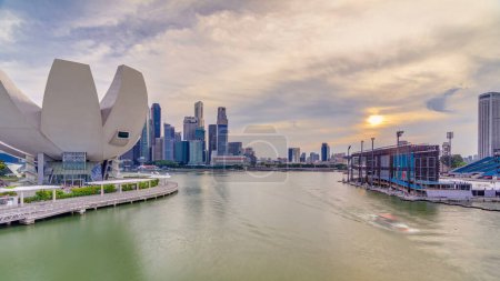 Foto de Arquitectura futurista diseño en forma de flor del Museo de Ciencias del Arte en el primer plano timelapse al atardecer. Rascacielos skyline ciudad de Singapur. - Imagen libre de derechos