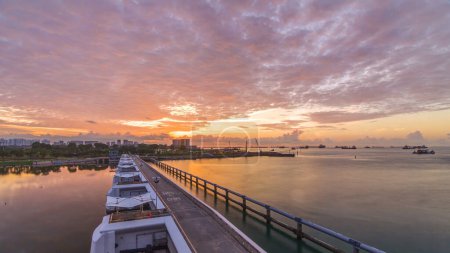 Foto de Hermoso amanecer en Marina Barrage timelapse panorámico. Cielo anaranjado y nubes con rayos de sol. Es el decimoquinto embalse de Singapur y el primero en el corazón de la ciudad. - Imagen libre de derechos