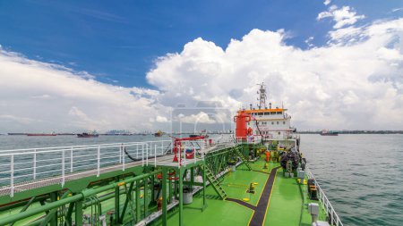 Photo for Green deck of the tanker under blue cloudy sky timelapse. Red crane with pipe moving on it by operator. Panoramic view - Royalty Free Image