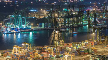 Téléchargez les photos : Port de Singapour timelapse de nuit. Oeil d'oiseau vue aérienne panoramique du port de fret asiatique le plus achalandé avec des centaines de navires chargeant des marchandises d'exportation et d'importation et des milliers de conteneurs dans le port - en image libre de droit