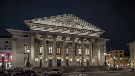 Foto de Teatro Nacional de Múnich o Teatro Nacional en la plaza Max Joseph noche timelapse hiperlapso. Iluminada vista histórica de la ópera, sede de la Ópera Estatal de Baviera. Alemania - Imagen libre de derechos