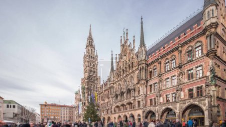 Main facade of the New Town Hall (Neues Rathaus) building at the northern part of Marienplatz timelapse hyperlapse in Munich. Fischbrunnen fountain in front. Cloudy sky. Bavaria, Germany.